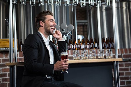 simsearch:6109-06685044,k - Handsome businessman holding a pint and calling in a pub Stock Photo - Premium Royalty-Free, Code: 6109-08489720