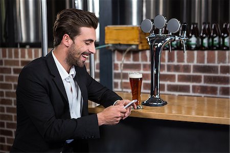 simsearch:6109-06685044,k - Handsome businessman texting on his phone in a pub Stock Photo - Premium Royalty-Free, Code: 6109-08489721