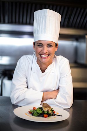 food and beverages hotel uniforms - Happy chef showing her dish in a commercial kitchen Stock Photo - Premium Royalty-Free, Code: 6109-08489859