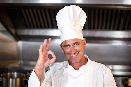 Chef smiling at camera in a commercial kitchen Stock Photo - Premium Royalty-Free, Code: 6109-08489836