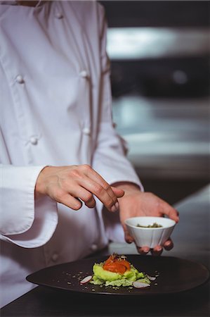 Chef sprinkling salt on dish in commercial kitchen Stock Photo - Premium Royalty-Free, Code: 6109-08489922