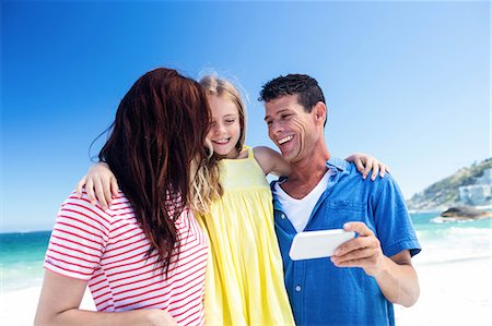 funny vacation - Cute family looking at smartphone on the beach Stock Photo - Premium Royalty-Free, Code: 6109-08434758