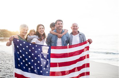 Cute family holding a US flag on the beach Photographie de stock - Premium Libres de Droits, Code: 6109-08434887