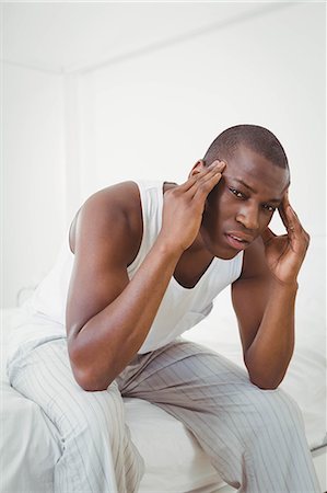 sad black people - Handsome man having headache sitting on his bed Stock Photo - Premium Royalty-Free, Code: 6109-08435276