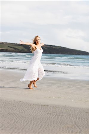 simsearch:6109-08481684,k - Beautiful blonde woman skipping in the coastline Foto de stock - Sin royalties Premium, Código: 6109-08435742