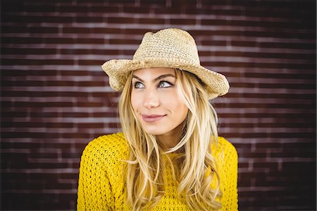 Portrait of blonde woman with straw hat on brick wall Stock Photo - Premium Royalty-Free, Code: 6109-08435818