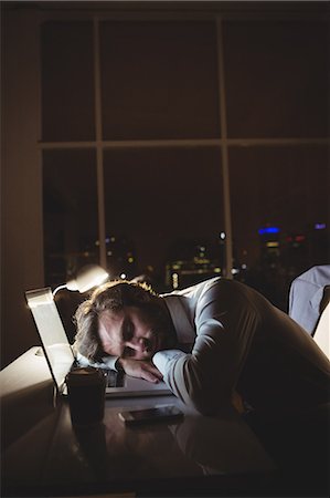 Businessman sleeping on his laptop at night Stock Photo - Premium Royalty-Free, Code: 6109-08581421