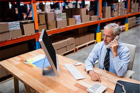 simsearch:400-04283915,k - Warehouse manager using a laptop talking on the phone Stock Photo - Premium Royalty-Free, Code: 6109-08581654