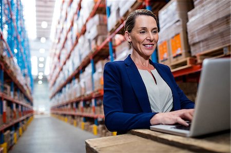 depot - Low angle view of warehouse manager looking her laptop Stock Photo - Premium Royalty-Free, Code: 6109-08581617