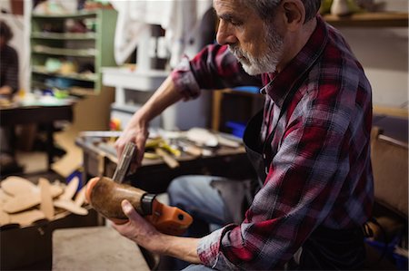 simsearch:6109-08582278,k - Profile view of cobbler stapling a shoe Stock Photo - Premium Royalty-Free, Code: 6109-08582268