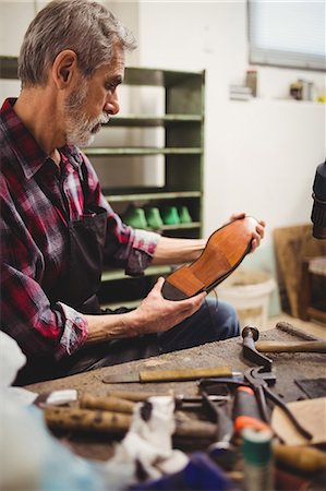 simsearch:6109-08582278,k - Profile view of cobbler looking the sole of a shoe Stock Photo - Premium Royalty-Free, Code: 6109-08582274