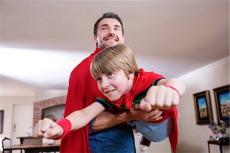 Father and son pretending to be superhero in living room Stock Photo - Premium Royalty-Free, Code: 6109-08536469