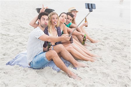 simsearch:6109-06781574,k - Group of friends sitting on the sand taking selfie with selfie stick Foto de stock - Sin royalties Premium, Código: 6109-08536863