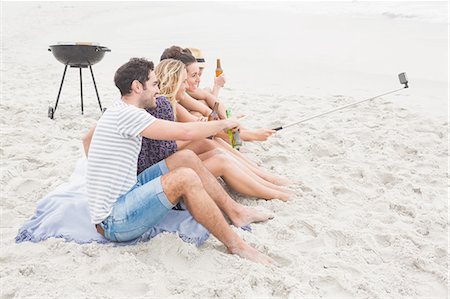 simsearch:6109-06781574,k - Group of friends sitting on the sand taking selfie with selfie stick Foto de stock - Sin royalties Premium, Código: 6109-08536862