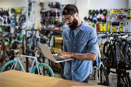 Bike mechanic checking at laptop Stock Photo - Premium Royalty-Free, Code: 6109-08537242