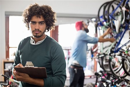 Hipster bike mechanic holding a clipboard Stock Photo - Premium Royalty-Free, Code: 6109-08537304
