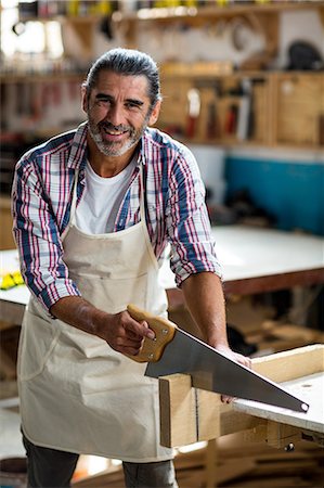 repairman - Carpenter cutting plank with hand saw Stock Photo - Premium Royalty-Free, Code: 6109-08537966