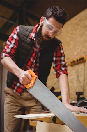 sawing - Carpenter sawing a plank of wood in carpentry Stock Photo - Premium Royalty-Free, Code: 6109-08689620