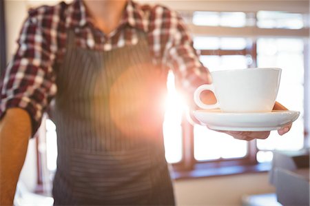 restaurant counter - Waiter holding cup of coffee in a cafe Stock Photo - Premium Royalty-Free, Code: 6109-08689731