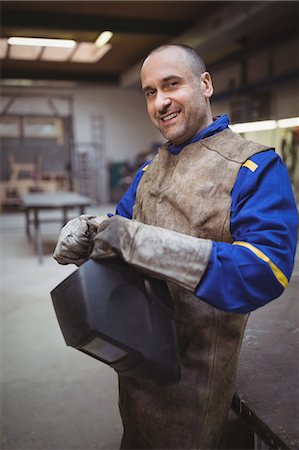 Side view of welder smiling and posing in his workshop Foto de stock - Sin royalties Premium, Código: 6109-08689888