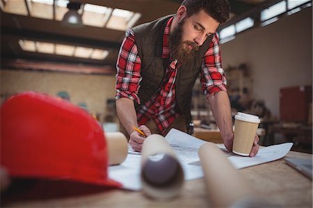 Carpenter working on a blueprint in workshop Stock Photo - Premium Royalty-Free, Code: 6109-08689941