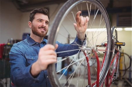 Mechanic repairing a bicycle wheel in his workshop Stock Photo - Premium Royalty-Free, Code: 6109-08689902