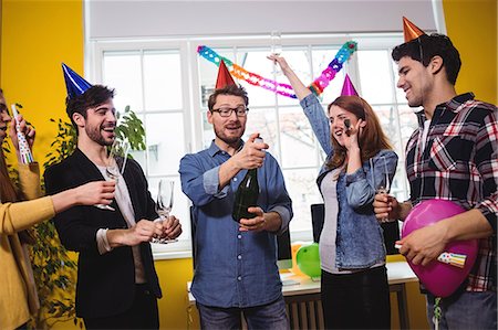 pictures man opening bottle - Businessman opening champagne bottle during birthday party with coworkers in creative office Stock Photo - Premium Royalty-Free, Code: 6109-08690334