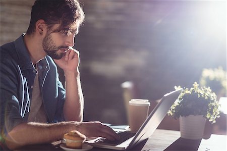 shop - Side view of young man concentrating on laptop at cafe Stock Photo - Premium Royalty-Free, Code: 6109-08690406