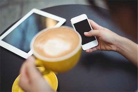 refreshment (food and drink) - Woman using mobile phone while having coffee in café Stock Photo - Premium Royalty-Free, Code: 6109-08764167