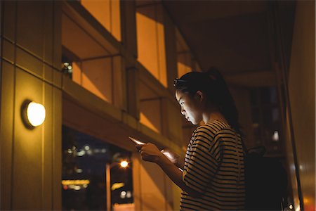 Young woman using digital tablet in passage at night Stock Photo - Premium Royalty-Free, Code: 6109-08764134