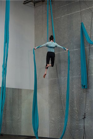 Gymnast exercising on blue fabric rope in fitness studio Stock Photo - Premium Royalty-Free, Code: 6109-08764236