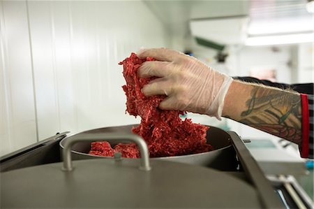 Close-up of butchers hand putting meat in mincer machine Stock Photo - Premium Royalty-Free, Code: 6109-08764572