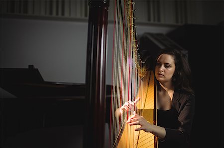 Attentive woman playing a harp in music school Stock Photo - Premium Royalty-Free, Code: 6109-08764701