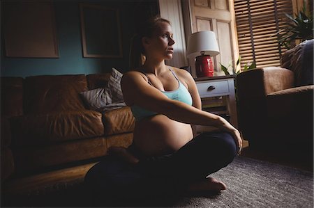 Pregnant woman performing stretching exercise in living room at home Stock Photo - Premium Royalty-Free, Code: 6109-08764922