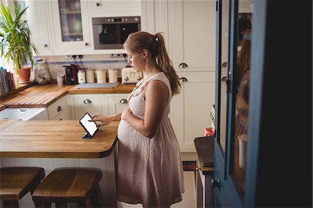 family computer kitchen - Pregnant woman using digital tablet in kitchen at home Photographie de stock - Premium Libres de Droits, Code: 6109-08764933