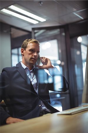 simsearch:6109-06685044,k - Businessman talking on the phone at desk in office Stock Photo - Premium Royalty-Free, Code: 6109-08765140