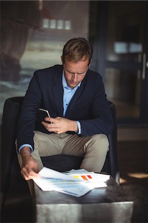 executive in the chair - Businessman with mobile phone checking financial reports in the office Stock Photo - Premium Royalty-Free, Code: 6109-08765134