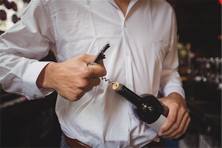 Mid section of bar tender opening a bottle of wine at bar counter Stock Photo - Premium Royalty-Free, Code: 6109-08782659