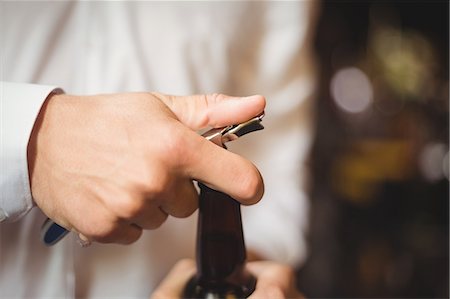 Close-up of bartender opening a beer bottle at bar counter Stock Photo - Premium Royalty-Free, Code: 6109-08782662