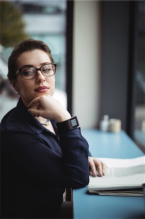 simsearch:6109-08700445,k - Thoughtful businesswoman sitting by table in cafe Stock Photo - Premium Royalty-Free, Code: 6109-08700444