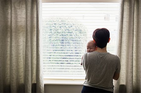 simsearch:6109-08390041,k - Mother holding her little baby and looking through window at home Stock Photo - Premium Royalty-Free, Code: 6109-08700743