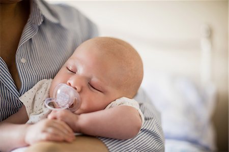 simsearch:6109-08390041,k - Close-up of baby with dummy sleeping in mother's arms at home Stock Photo - Premium Royalty-Free, Code: 6109-08700760