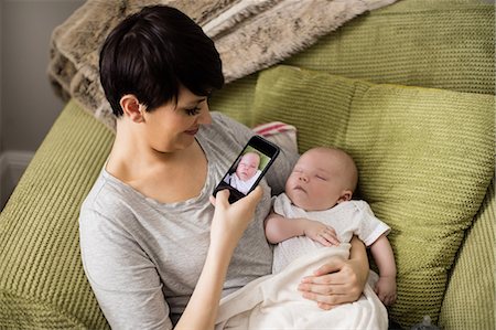 simsearch:6109-08390041,k - Mother taking picture of her baby from mobile phone in living room at home Stock Photo - Premium Royalty-Free, Code: 6109-08700729