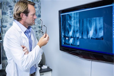 simsearch:614-06813654,k - Thoughtful dentist examining an x-ray on the monitor in clinic Foto de stock - Sin royalties Premium, Código: 6109-08700853