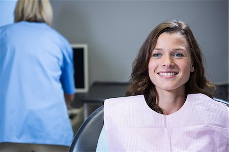 dentist with patient in exam room - Smiling patient sitting on dentist's chair at clinic Stock Photo - Premium Royalty-Free, Code: 6109-08700817