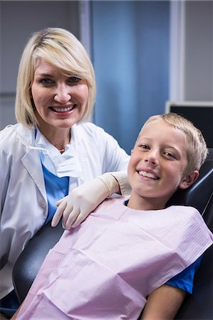 dentist with patient in exam room - Portrait of smiling dentist and young patient at dentist clinic Stock Photo - Premium Royalty-Free, Code: 6109-08700835