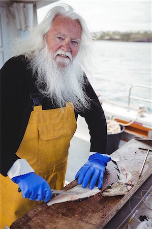 Portrait of fisherman filleting fish in boat Stock Photo - Premium Royalty-Free, Code: 6109-08701064