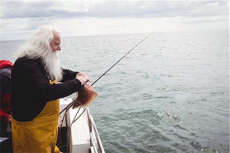 Fisherman on the boat catching a fish Stock Photo - Premium Royalty-Free, Code: 6109-08701101