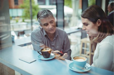 restaurant friends - Man and woman discussing over mobile phone in the cafeteria Stock Photo - Premium Royalty-Free, Code: 6109-08701371
