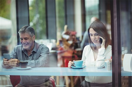 simsearch:6109-08690411,k - Man text messaging while woman talking on mobile phone in the cafeteria Stock Photo - Premium Royalty-Free, Code: 6109-08701375